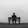 Hombre de espaldas, viendo al horizonte, escenario gris que transmite el sentimiento de soledad