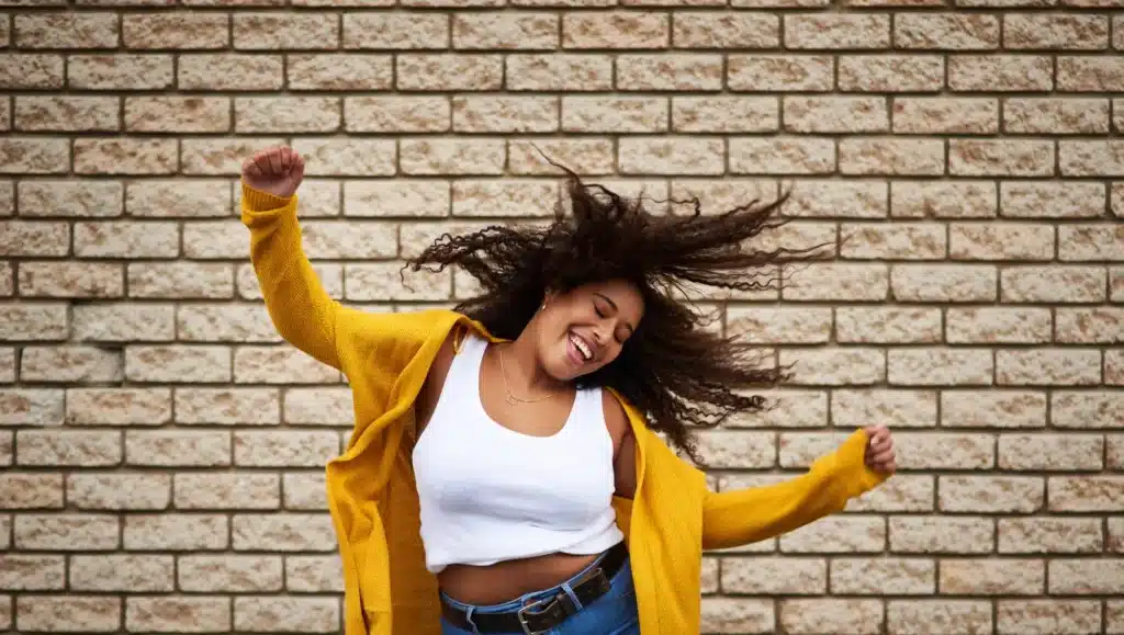 Mujer bailando feliz con ojos cerrandos, simboliza la libertad