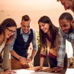 Grupo de colaboradores sonriendo, colaborando en un proyecto.