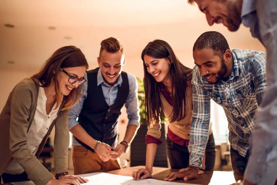Grupo de colaboradores sonriendo, colaborando en un proyecto.
