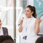 Mujer ejecutiva hablando por micrófono ante una audiencia